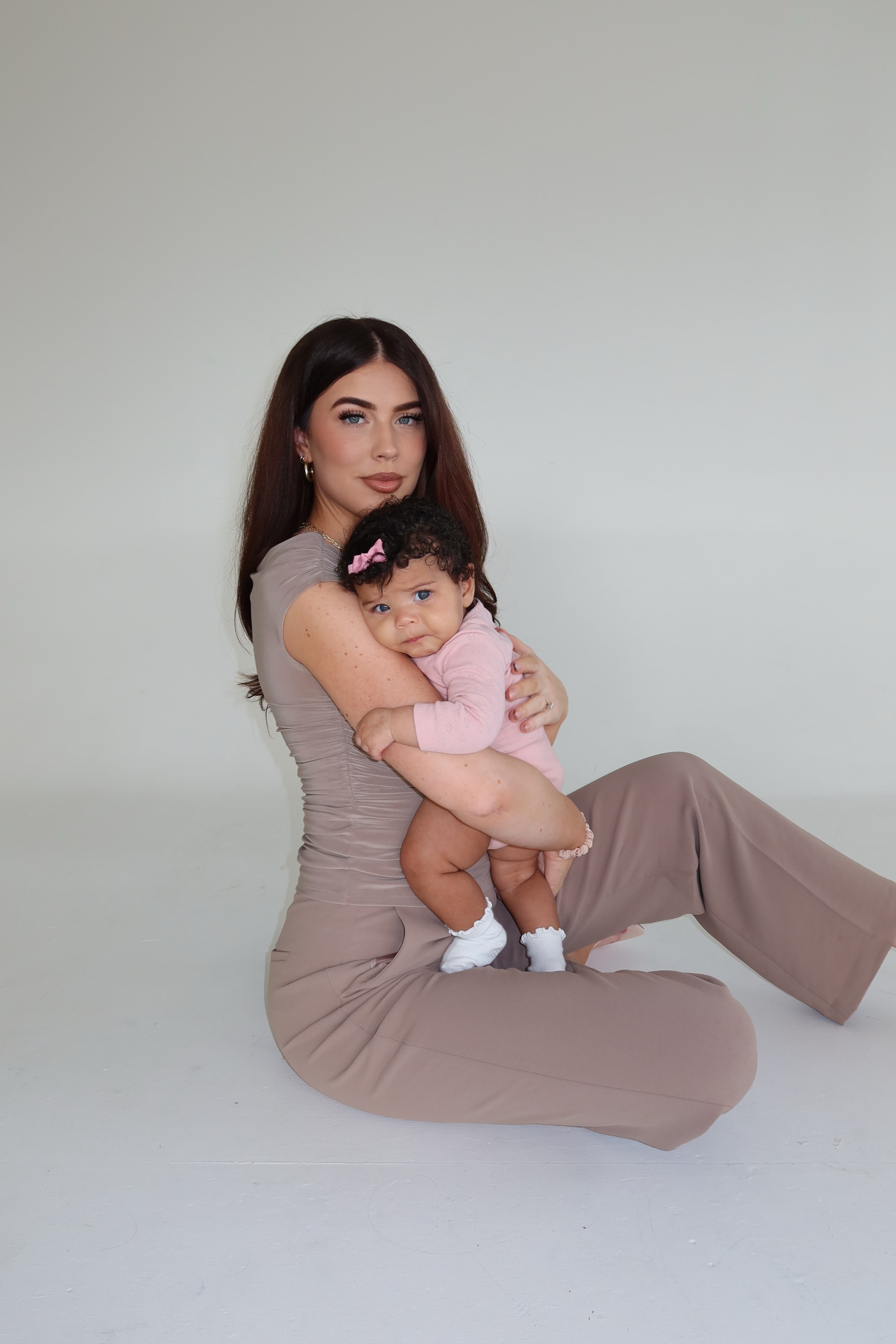 Woman holding a baby against a plain background